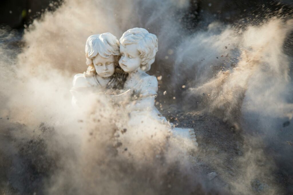 Two White Concrete Statues in a cloud of Dust